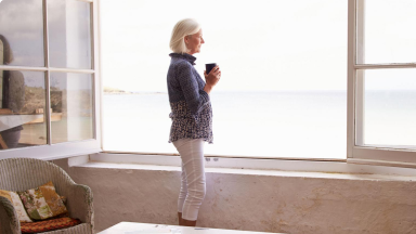 Žena u okna se šálkem kávy