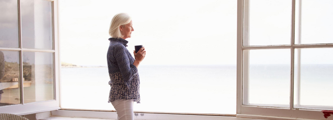 Žena u okna se šálkem kávy